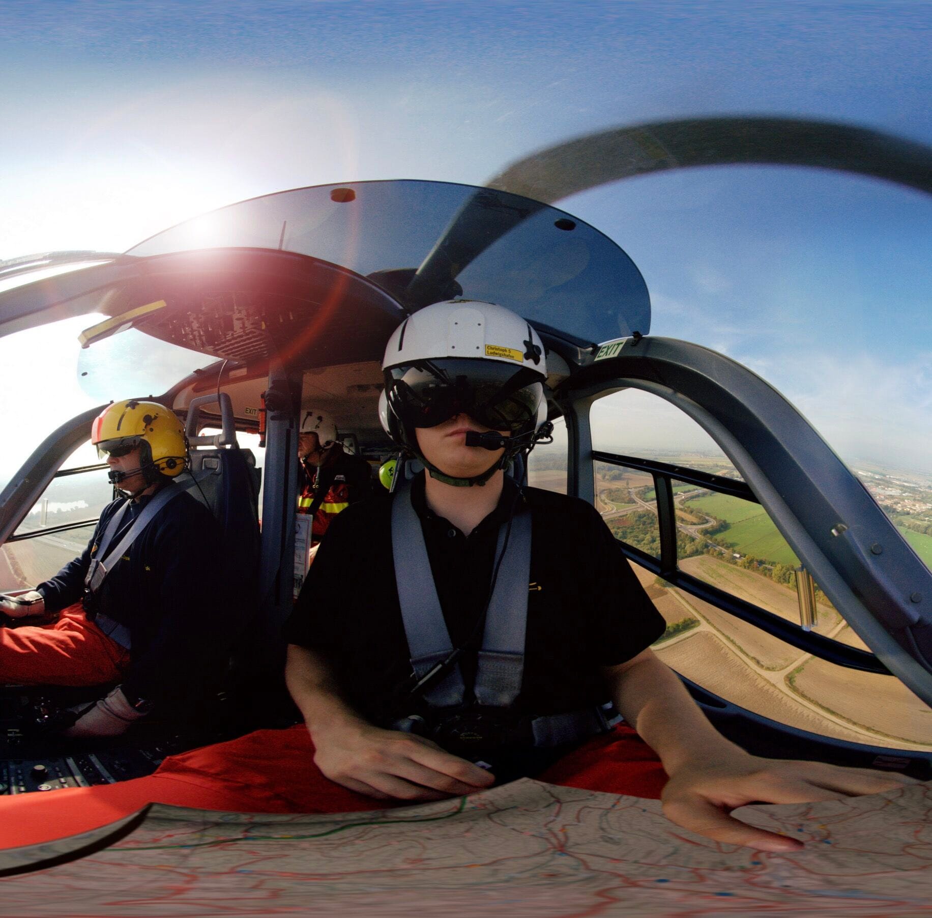 Person im Helikopter mit Karte und Helm