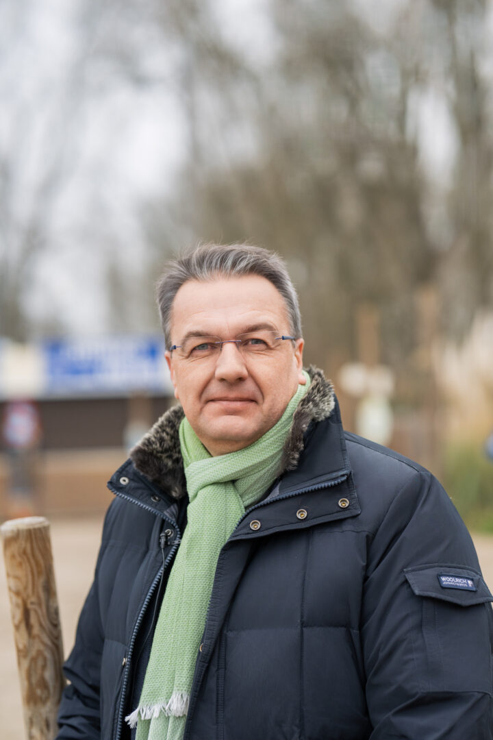 Man in winter coat with green scarf, outside