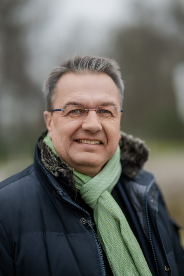 Smiling man with glasses and green scarf