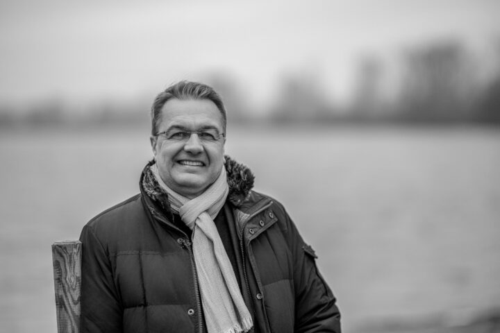Man smiling in winter coat and scarf by the river