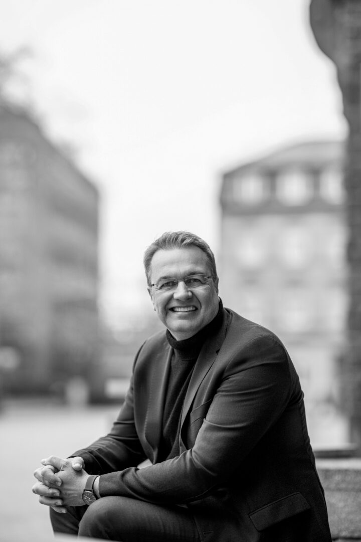 Smiling man in a suit sitting outside.