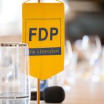 Gelbes FDP-Banner auf einem Tisch.