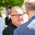 Zwei Männer unterhalten sich im Freien, sonniger Tag.