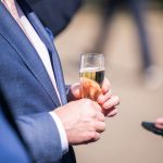 Person hält Sektglas in der Hand, elegantes Outfit.