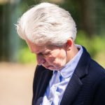 Person mit weißem Haar schaut nach unten.