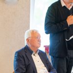 Zwei Männer bei einer Gesprächsrunde in einem Raum.