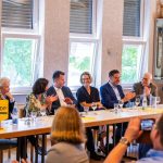 Diskussionsteilnehmer am Tisch in einem Meetingraum.