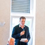 Person hält Mikrofon und spricht vor Publikum.