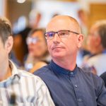 Mann mit Brille sitzt konzentriert in Publikum.