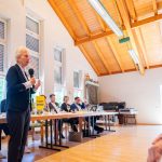 Frau spricht bei FDP-Veranstaltung in Holzsaal.