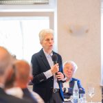 Frau spricht bei Konferenz vor Publikum mit Mikrofon.
