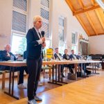 Person spricht bei einer Veranstaltung mit Publikum.