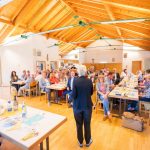 Person spricht vor Gruppe in hellem Saal.
